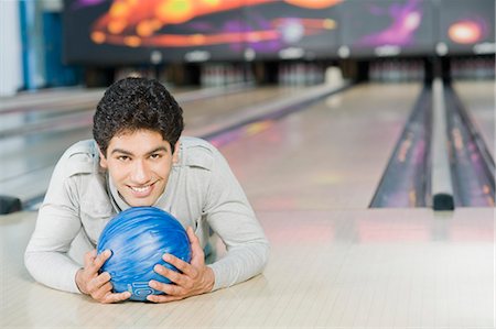 simsearch:630-03481667,k - Young man lying with a bowling ball in a bowling alley Foto de stock - Royalty Free Premium, Número: 630-03481546
