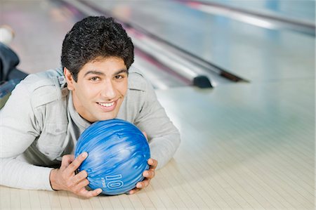 simsearch:630-03481667,k - Young man lying with a bowling ball in a bowling alley Foto de stock - Royalty Free Premium, Número: 630-03481548