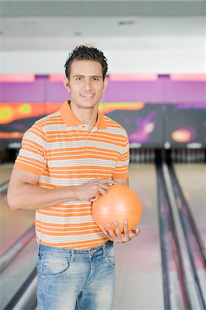 simsearch:630-03481666,k - Jeune homme tenant une boule de bowling dans une allée de quilles Photographie de stock - Premium Libres de Droits, Code: 630-03481553