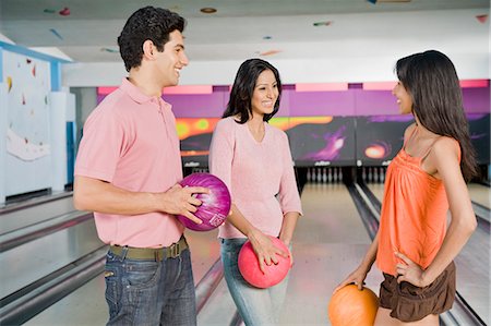 simsearch:630-03481678,k - Young couple with their friend holding bowling balls in a bowling alley Foto de stock - Royalty Free Premium, Número: 630-03481577