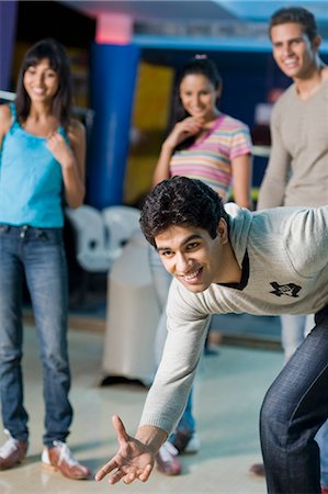 Young man bowling in a bowling alley and his friends watching him Stock Photo - Premium Royalty-Free, Code: 630-03481604