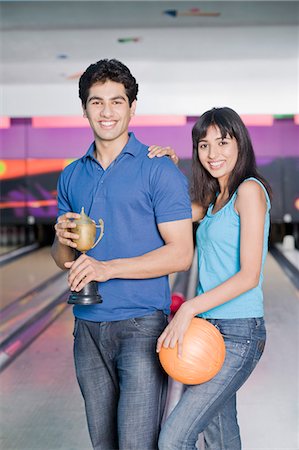 Jeune couple avec une boule de bowling et un trophée dans un bowling Photographie de stock - Premium Libres de Droits, Code: 630-03481614