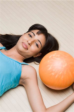 simsearch:630-03481667,k - Young woman lying with a bowling ball in a bowling alley Foto de stock - Royalty Free Premium, Número: 630-03481634