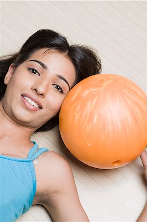 simsearch:630-03481667,k - Young woman lying with a bowling ball in a bowling alley Foto de stock - Royalty Free Premium, Número: 630-03481635