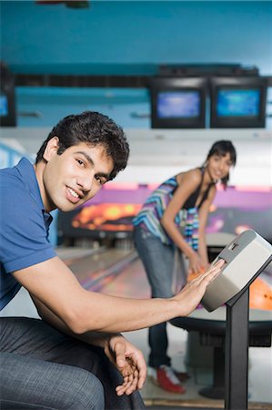 simsearch:630-03481611,k - Young man operating the control panel and his friend looking at him in a bowling alley Stock Photo - Premium Royalty-Free, Code: 630-03481651