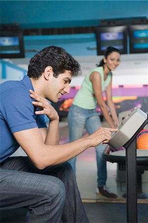 simsearch:693-06015216,k - Young man operating the control panel and his friend looking at him in a bowling alley Stock Photo - Premium Royalty-Free, Code: 630-03481652