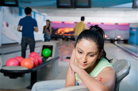 simsearch:630-03481602,k - Jeune femme pense avec ses amis en arrière-plan dans une ruelle de bowling Photographie de stock - Premium Libres de Droits, Code: 630-03481675