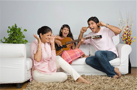 Girl singing and her parents covering their ears Foto de stock - Royalty Free Premium, Número: 630-03482008