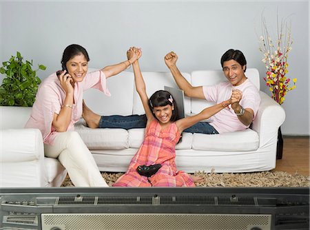 simsearch:630-03482008,k - Parents with their daughter cheering over video game Foto de stock - Sin royalties Premium, Código: 630-03482001