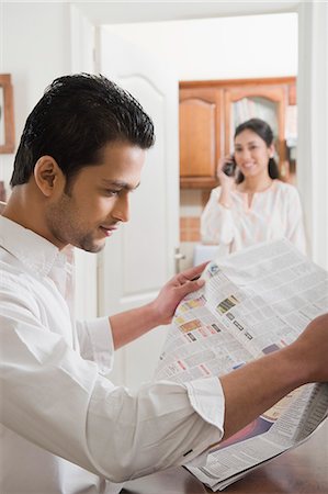 Man reading a newspaper while his wife using a mobile phone Stock Photo - Premium Royalty-Free, Code: 630-03482591