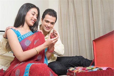 Woman putting on bangles with her husband sitting beside her Foto de stock - Royalty Free Premium, Número: 630-03482687