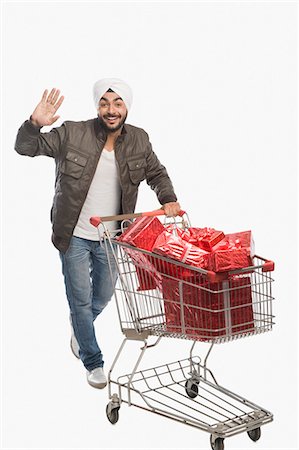 person with shopping cart - Man pushing a shopping cart of gifts Stock Photo - Premium Royalty-Free, Code: 630-03482758