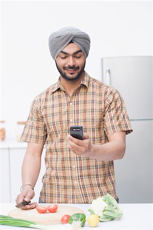 Man chopping vegetables and using a mobile phone Stock Photo - Premium Royalty-Free, Code: 630-03482834