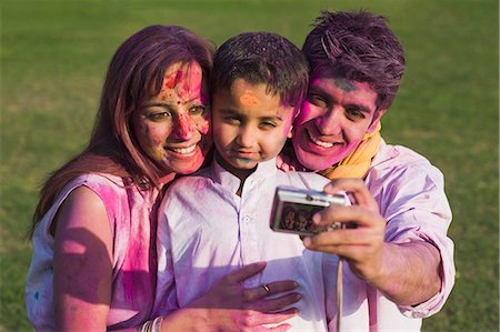 Family taking picture of themselves with a digital camera on Holi Foto de stock - Sin royalties Premium, Código: 630-03483042