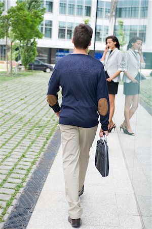 Man walking with briefcase, woman talking on cell phone in background Stock Photo - Premium Royalty-Free, Code: 632-05400888