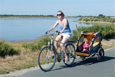 family bicycling - Woman riding along bicycle path with children in bicycle trailer Stock Photo - Premium Royalty-Free, Code: 632-05401110