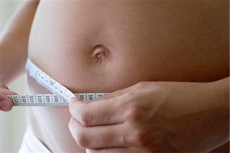 female and weight gain - Pregnant woman measuring her belly with measuring tape, cropped Stock Photo - Premium Royalty-Free, Code: 632-05554024