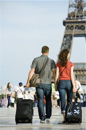 europe couple traveling - Couple walking with rolling luggage near Eiffel Tower, Paris, France Foto de stock - Sin royalties Premium, Código: 632-05554045