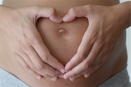 simsearch:632-05554036,k - Pregnant woman's hands making heart shape on her belly, cropped Foto de stock - Sin royalties Premium, Código: 632-05554046