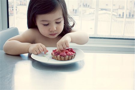 Little girl eating raspberry tart Stock Photo - Premium Royalty-Free, Code: 632-05553397