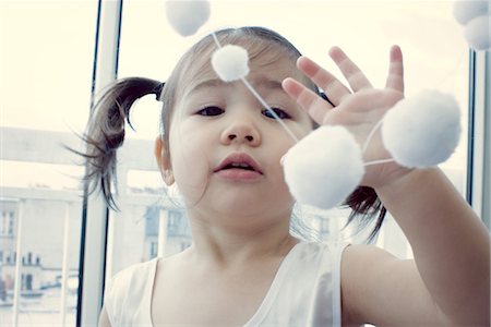 Little girl playing with hanging decoration Stock Photo - Premium Royalty-Free, Code: 632-05553421