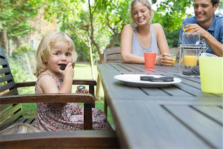 picnic table - Little girl eating snack with her parents outdoors Stock Photo - Premium Royalty-Free, Code: 632-05553648