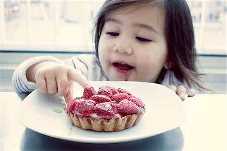Little girl getting taste of raspberry tart Stock Photo - Premium Royalty-Free, Code: 632-05553661