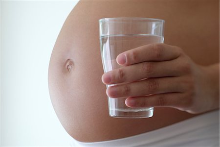 Woman holding glass of water beside pregnant belly, cropped Stock Photo - Premium Royalty-Free, Code: 632-05553684