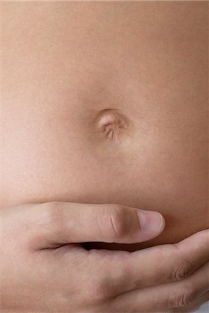 Close-up of woman's hand on pregnant belly Stock Photo - Premium Royalty-Free, Code: 632-05553795