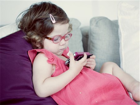 simsearch:649-06488434,k - Little girl reclining on couch looking at cell phone Fotografie stock - Premium Royalty-Free, Codice: 632-05553817