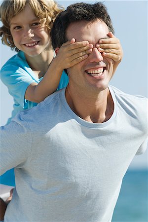 father and son beach piggyback - Boy covering father's eyes with hands Stock Photo - Premium Royalty-Free, Code: 632-05553824