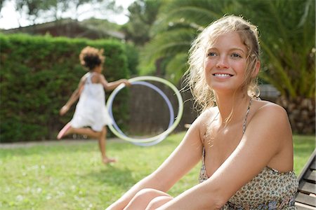 Woman relaxing outdoors, girl playing in background Stock Photo - Premium Royalty-Free, Code: 632-05604084