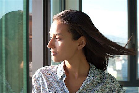 Woman looking out of window, sunshine on face Stock Photo - Premium Royalty-Free, Code: 632-05604085