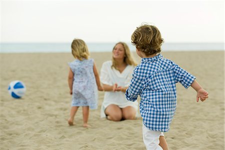 people run back view - Boy playing on beach, family in background Stock Photo - Premium Royalty-Free, Code: 632-05604138