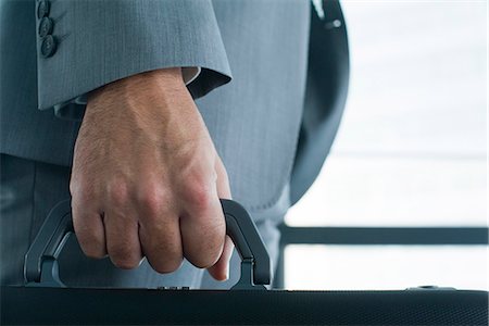 Executive's hand carrying briefcase, mid section, close-up Stock Photo - Premium Royalty-Free, Code: 632-05604141