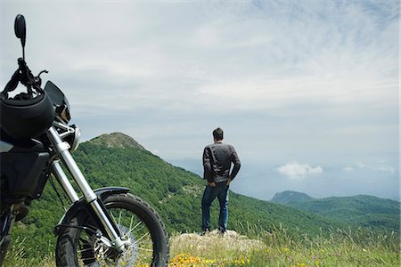 Man standing on rock looking at mountain view, motorcycle in foreground, rear view Foto de stock - Sin royalties Premium, Código: 632-05603814