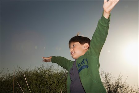 simsearch:632-03424651,k - Boy playing outdoors with arms raised in air Stock Photo - Premium Royalty-Free, Code: 632-05759484