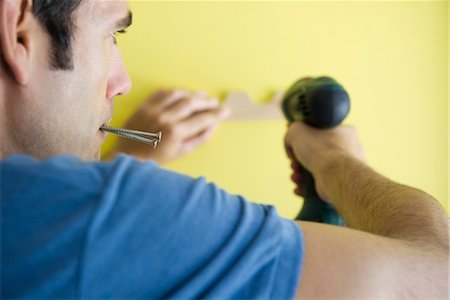 pictures of a man holding a drill - Man using power drill, biting screws in mouth Stock Photo - Premium Royalty-Free, Code: 632-05759482