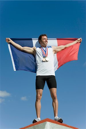 Male athlete being honored on podium, holding up French flag Stock Photo - Premium Royalty-Free, Code: 632-05759588