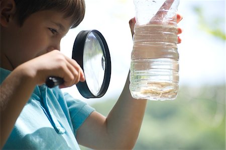 Boy looking at fish in water bottle with magnifying glass Stock Photo - Premium Royalty-Free, Code: 632-05759713