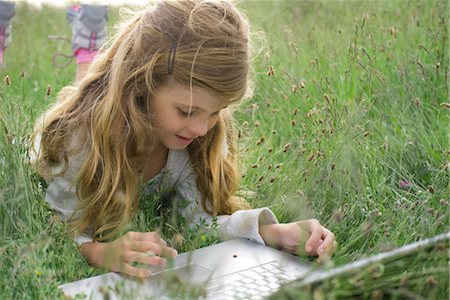 Girl lying in grass, watching ladybug crawling on laptop computer Stock Photo - Premium Royalty-Free, Code: 632-05759843