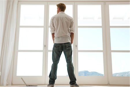 Man looking out window, rear view Stock Photo - Premium Royalty-Free, Code: 632-05759856