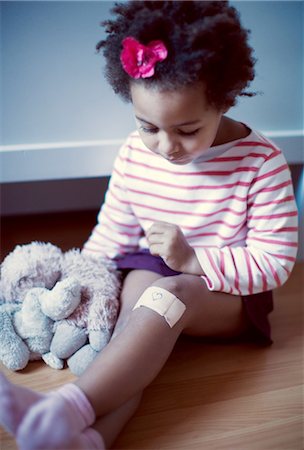scratch (flesh wound) - Little girl looking at adhesive bandage on knee Stock Photo - Premium Royalty-Free, Code: 632-05759898