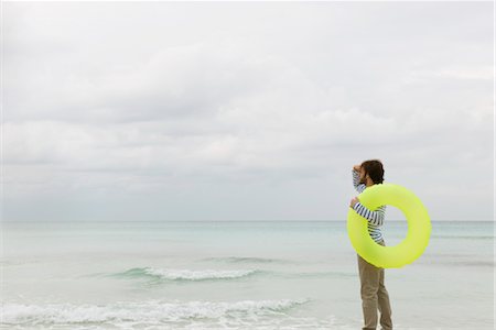 simsearch:632-06318057,k - Young man carrying swimming ring, looking into distance Stock Photo - Premium Royalty-Free, Code: 632-05759968
