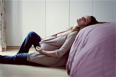 Pregnant woman leaning against bed resting Stock Photo - Premium Royalty-Free, Code: 632-05760023