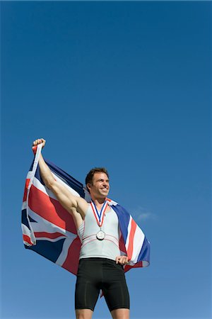 Male athlete on winner's podium, holding up British flag Stock Photo - Premium Royalty-Free, Code: 632-05760123