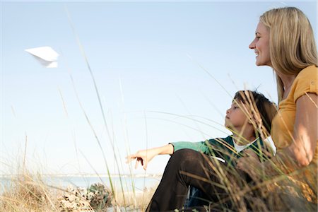 Boy sitting with his mother, throwing paper airplane Stock Photo - Premium Royalty-Free, Code: 632-05760206