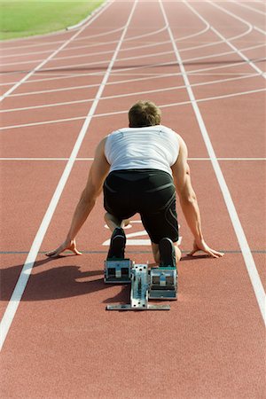 race - Runner crouched at startling line, rear view Stock Photo - Premium Royalty-Free, Code: 632-05760214