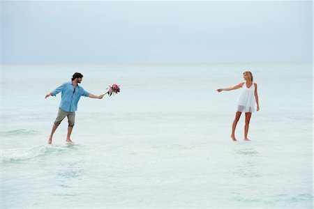 Couple walking on water towards each other, man holding out bouquet Stock Photo - Premium Royalty-Free, Code: 632-05760268