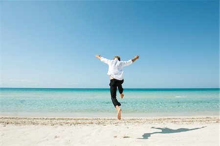 simsearch:632-05816759,k - Homme sautant plein ciel sur la plage, vue arrière Photographie de stock - Premium Libres de Droits, Code: 632-05760335